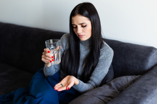 Girl holding glass of water and medicine